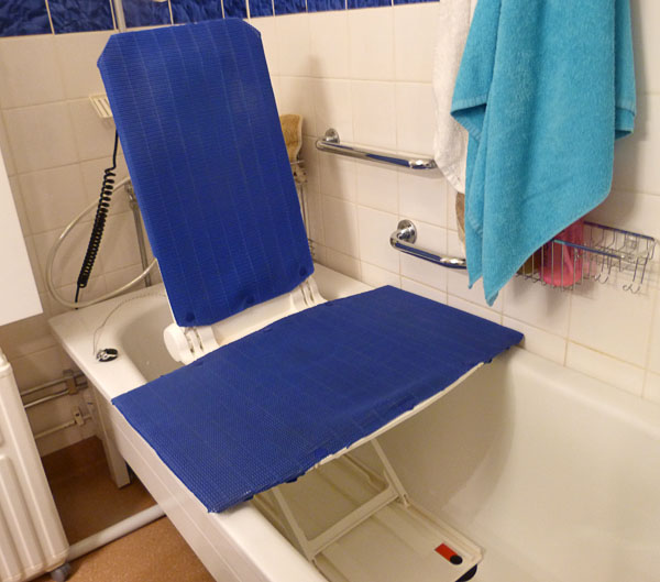 In the bathtub there is a padded seat with a cross underneath.