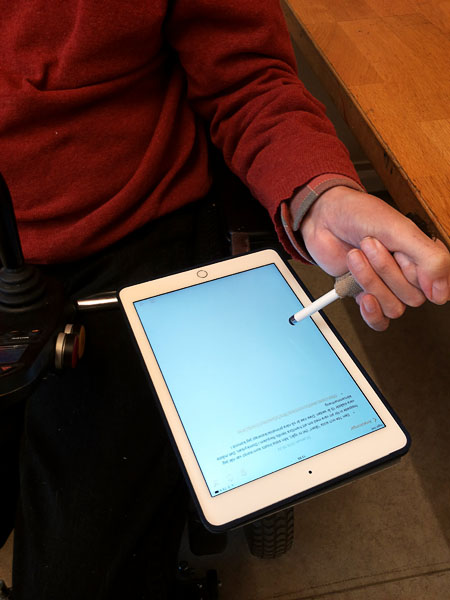 Användaren skriver anteckningar på sin Ipad som ligger på Ipad-hållaren